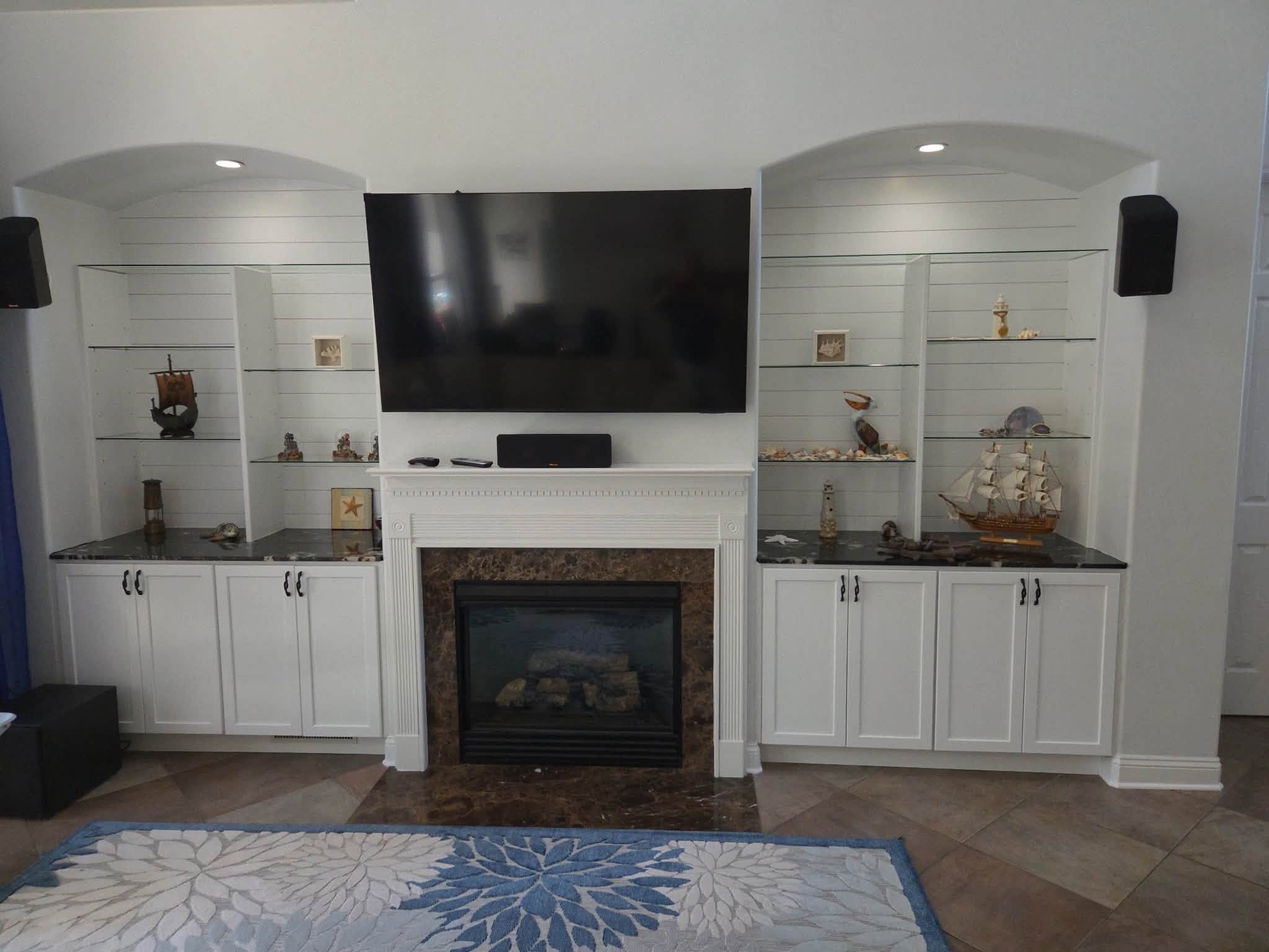 Finished media wall with glass shelves, cabinets and fireplace, published by McGrath Handyman Services